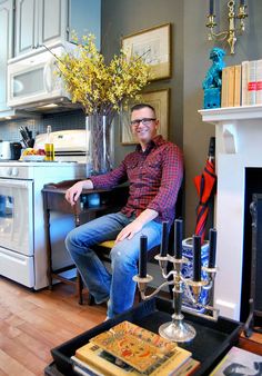 a man sitting in a chair next to a stove top oven and table with books on it