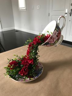 a flower arrangement in a tea cup on a table