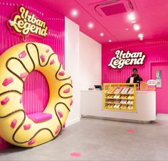 a man standing in front of a giant donut shaped doughnut shop with pink walls