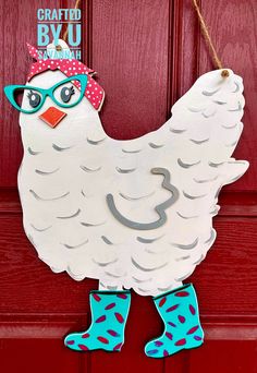 a white chicken with glasses and a pink hat hanging on a red front door ornament