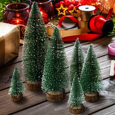 small christmas trees sitting on top of a wooden table next to other decorations and gifts