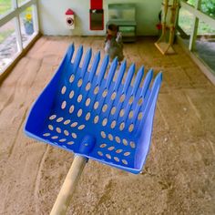 a blue plastic brush sitting on top of a wooden stick in front of a window