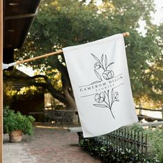 a white banner hanging from a clothes line on the side of a building with trees in the background