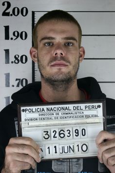 a mug shot of a man holding up a license plate