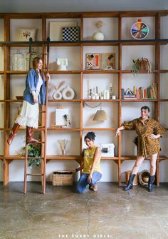 three people are posing in front of a bookshelf