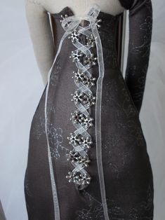 a mannequin wearing a black dress with white lace and beaded trims