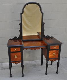 an antique vanity with mirror and stool inlaid to the top, on display against a brick wall