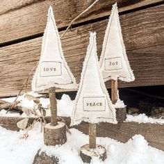 three small white trees sitting on top of snow covered ground