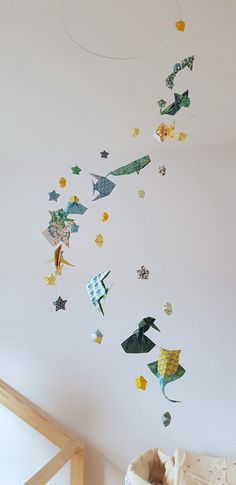 a baby crib with an animal mobile hanging from it's side and stars on the ceiling