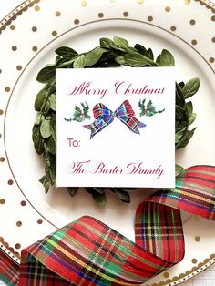 a christmas card sitting on top of a plate next to a red and green ribbon