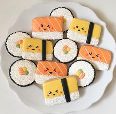 four decorated cookies on a white plate with sushi in the shape of eyes and hands