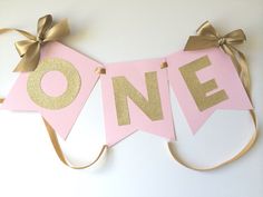 a pink and gold banner with the word one on it