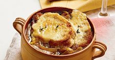 two pieces of bread sit in a pot filled with soup on a table next to utensils and napkins