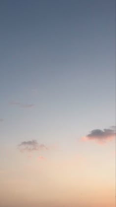 two people are flying kites on the beach at sunset