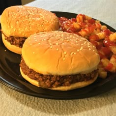 two hamburgers and fries on a black plate