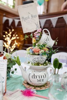 there is a tea set on top of each other at the table with flowers in it