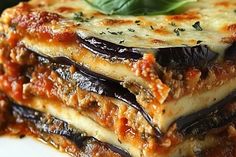 three slices of lasagna stacked on top of each other with basil leaves and cheese