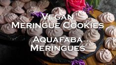 vegan meringue cookies are arranged on a wooden platter with pink flowers