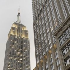 the empire building in new york city is lit up at night, with other tall buildings behind it