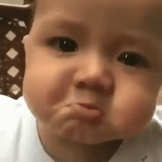 a baby is making a face while wearing a white shirt and tie with his tongue out