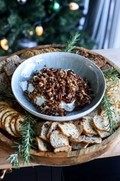 a platter with crackers, cheese and nuts on it next to a christmas tree