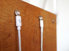 an apple charger plugged in to a wooden wall with two wires attached on it