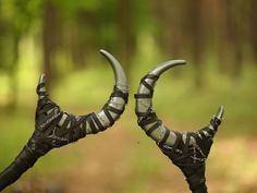 two metal horns with chains on them in the woods