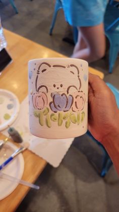 a person holding up a coffee cup with a bear on it