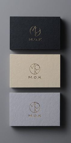 three business cards with the letter m o k on them, all in gold and black