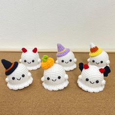 four crocheted little white ghostes with hats on their heads and one has a pumpkin in its mouth