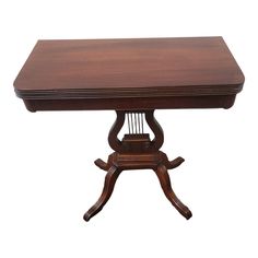 a wooden table with two legs and a square top on an ornate pedestal, against a white background