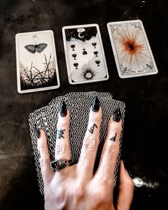 a person's hand with tattoos on their fingers next to four playing cards and a butterfly