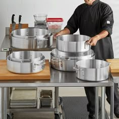 a man standing in front of a bunch of pots on top of a metal table