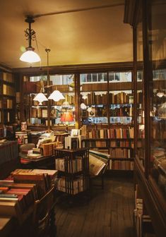 a room filled with lots of books on top of wooden flooring next to a window