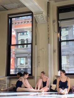 three women sitting on the floor in front of two windows