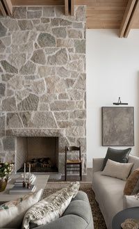 a living room filled with furniture and a fire place in front of a stone wall