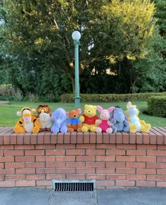 a group of stuffed animals sitting on top of a brick wall next to a street light