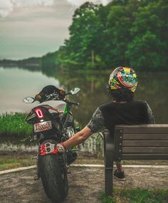 a person sitting on a bench next to a motorcycle and a motorbike in the background