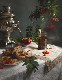 a table topped with a plate of food next to a vase filled with red berries