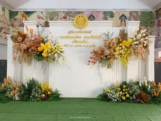 an arrangement of flowers and greenery in front of a wall with words on it