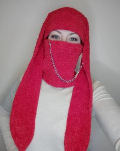 a woman wearing a red scarf and covering her face with a chain around her neck