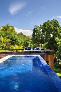 an empty swimming pool in the middle of a lush green yard with blue tiles on it