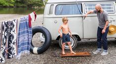 a man standing next to a little boy in front of an old vw bus