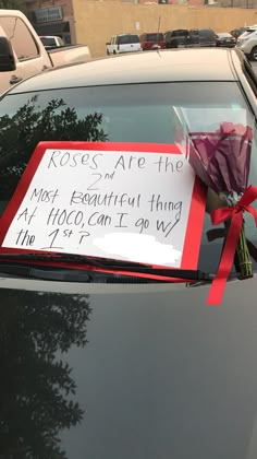 a bouquet of flowers sitting on the hood of a car with a note attached to it