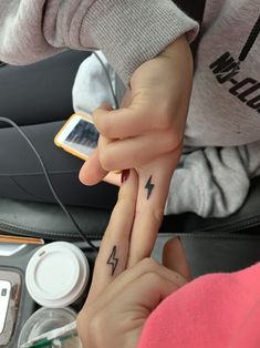 two people with matching tattoos holding each other's fingers and pointing at something on their finger