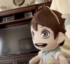 a stuffed doll is sitting in front of a television set with an evil look on its face