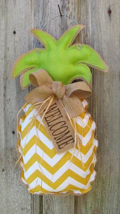 a pineapple shaped ornament hanging on a wooden fence with burlocks