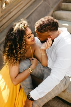 a man and woman sitting next to each other on the steps in front of stairs