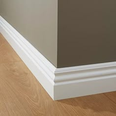 the corner of a room with wood flooring and white trim on the wall next to it