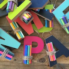 colorful wooden letters tied with twine and rope on top of wood planks that spell out the letter p